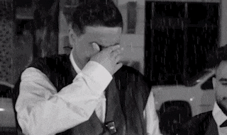 a man in a suit and tie is covering his face in the rain .