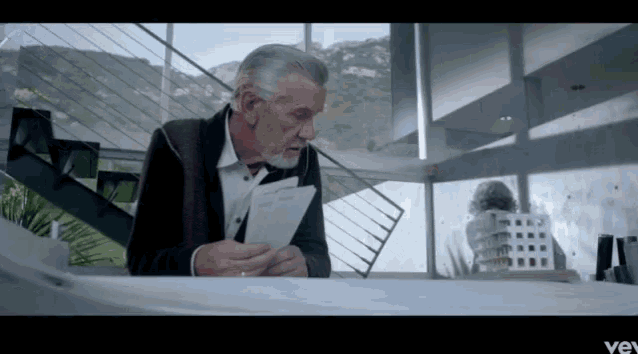a man is sitting at a table reading a letter