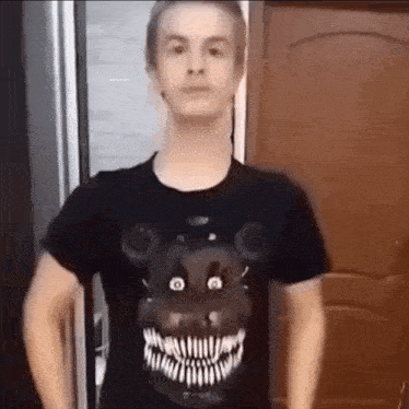 a young man wearing a black t-shirt with a teddy bear face on it .