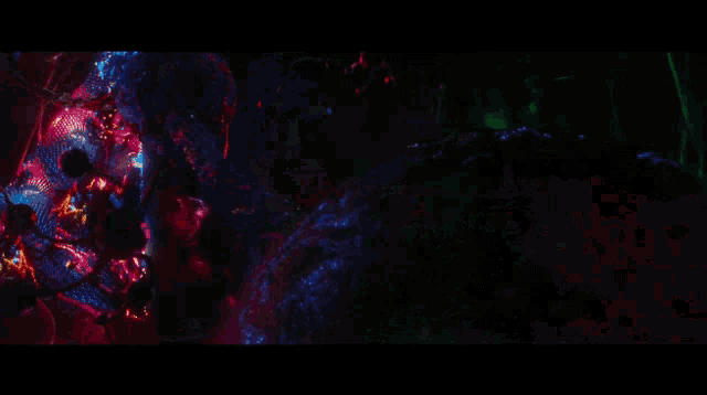 a man in a suit is standing in a dark room with a lot of fire