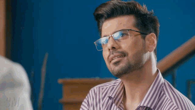 a man wearing glasses and a striped shirt is looking at something