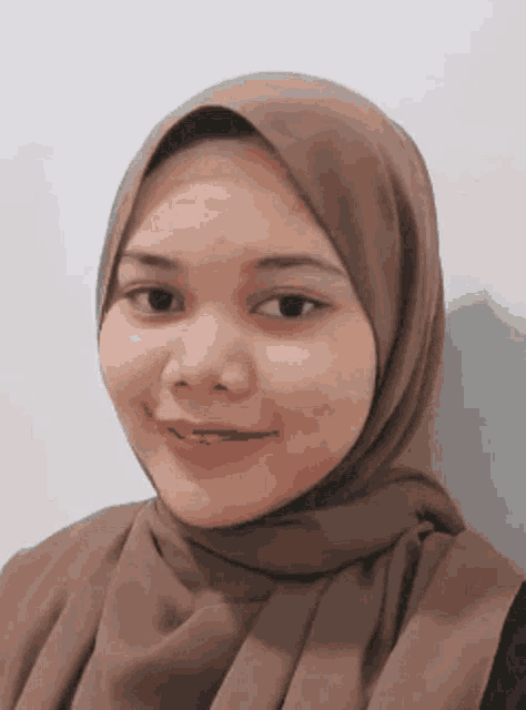 the woman is wearing a brown hijab and smiling for the camera