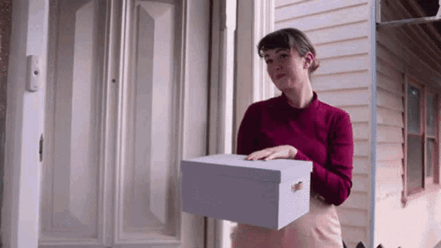 a woman in a red shirt is holding a white box