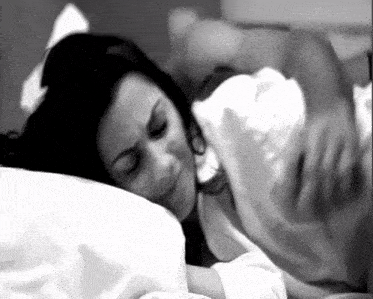 a black and white photo of a woman laying on a bed with her eyes closed