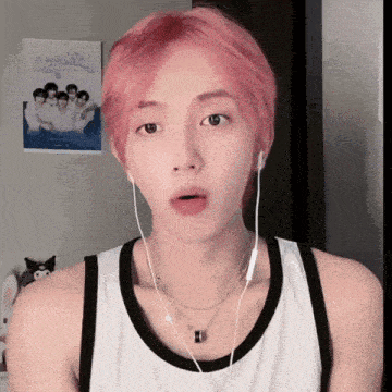 a young man with pink hair is wearing headphones