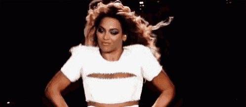 a woman with long red hair is wearing a white crop top and dancing .