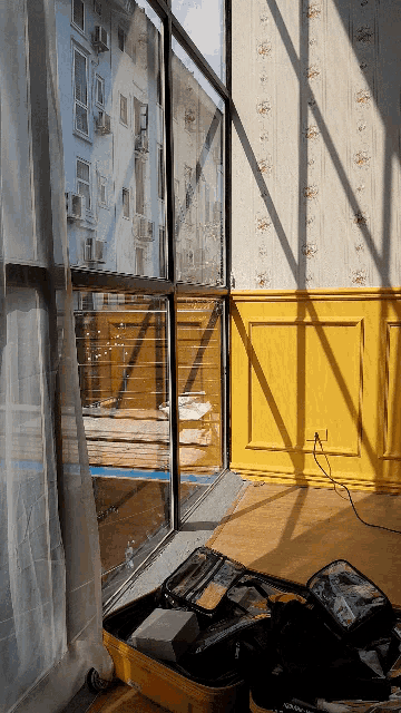 a yellow suitcase sits in front of a window in a room