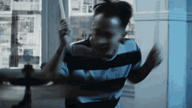 a man in a black and white striped shirt holds a bat