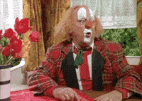 a clown is sitting at a table with his mouth open .