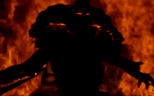 a silhouette of a person standing in front of fire