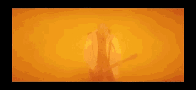 a man is playing a guitar in front of a fire in a dark room .