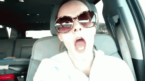 a woman wearing sunglasses yawning while sitting in a car