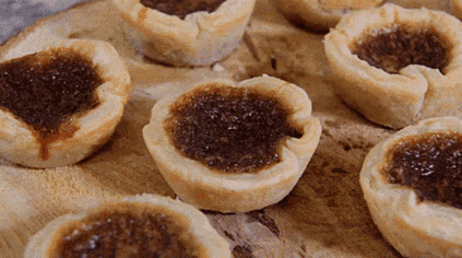 a wooden table topped with a bunch of small pastries with a brown filling