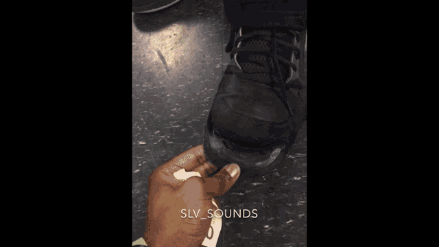 a person holding a piece of paper next to a shoe with the words slv sounds written on the bottom