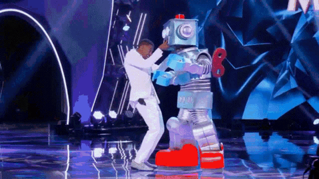 a man in a white suit is dancing on a stage with a robot .