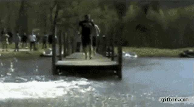 a group of people are walking across a bridge over a body of water .