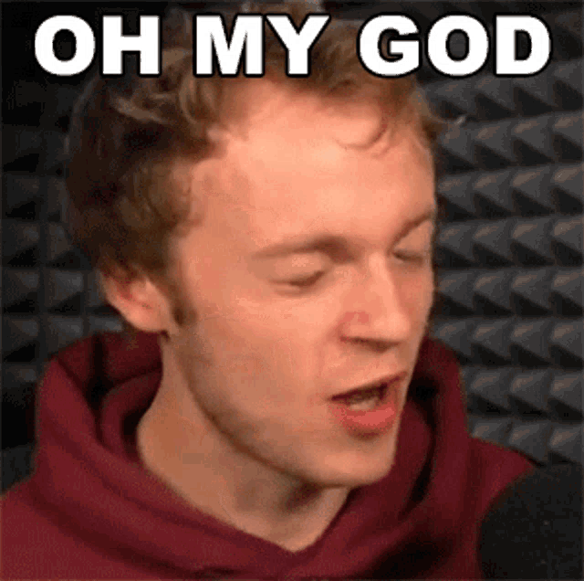 a man in a red hoodie is talking into a microphone and the words oh my god are above him .