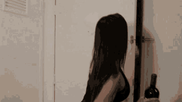 a woman is holding a bottle of wine in her hand while standing in front of a door .