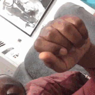 a close up of a person 's fist being held up in front of a computer screen .