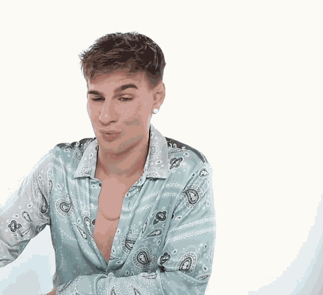a man wearing a blue paisley shirt with a necklace around his neck