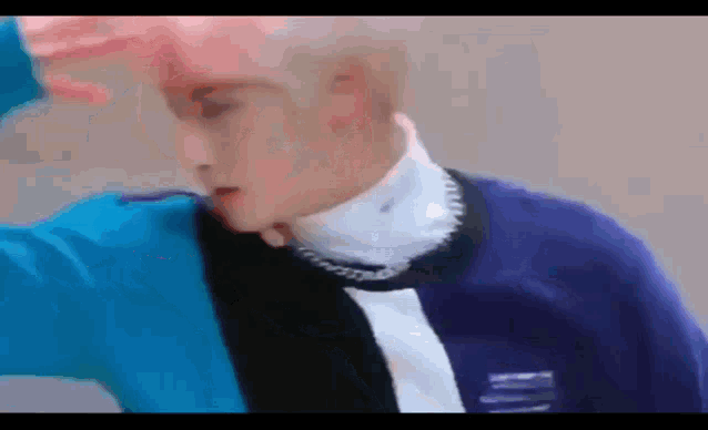 a close up of a person wearing a blue and black sweater and a white turtleneck .