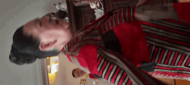 a woman wearing a red and black striped shirt is standing in a room