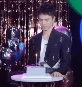 a man is sitting at a table with a cake and a candle .