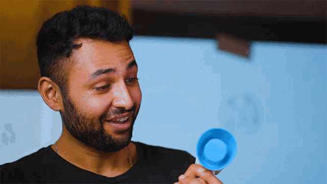 a man with a beard is holding a small blue object