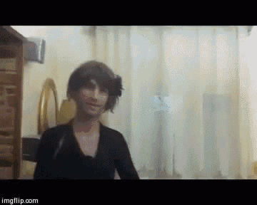 a woman in a black dress is standing in front of a mirror