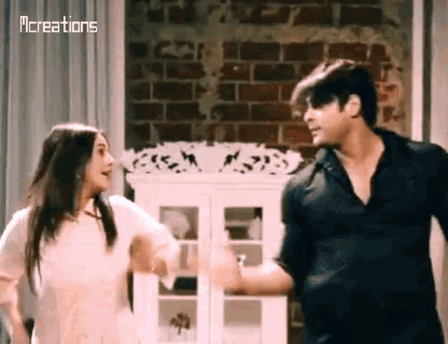 a man and a woman are dancing together in front of a brick wall .