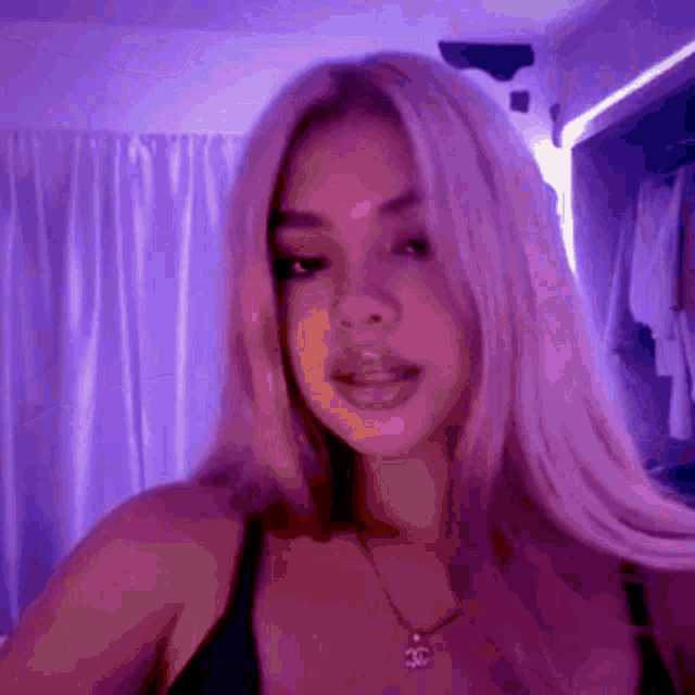 a woman with long blonde hair is standing in front of a purple wall .