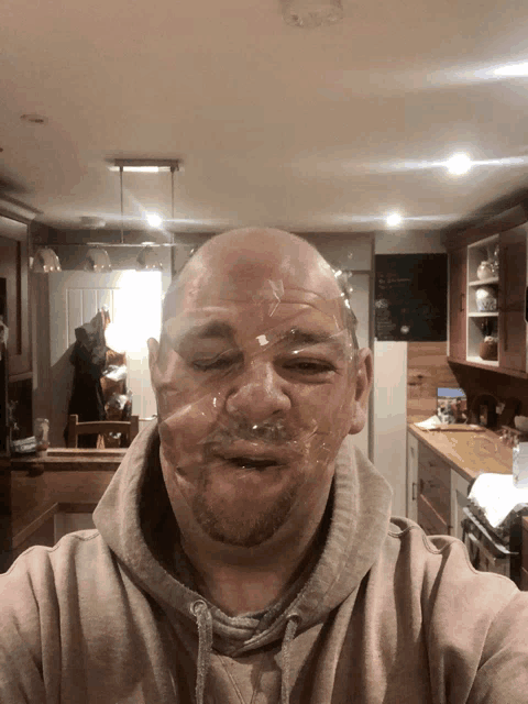 a man with duct tape on his face takes a selfie in a kitchen