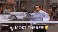 a man is running down a street with a sign that says `` almost there !!! ''