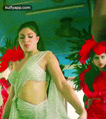 a woman in a white dress is dancing in front of a group of women in red dresses .