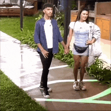 a man and a woman are holding hands while walking on a sidewalk