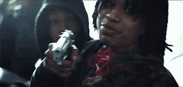 a man in a camo hoodie holds a gun