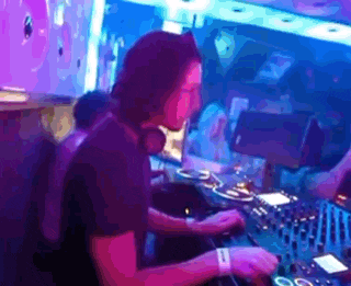 a man wearing headphones is playing a dj set in a dark room