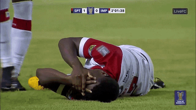 a soccer player is laying on the ground with his head in his hands during a game between spt and imp