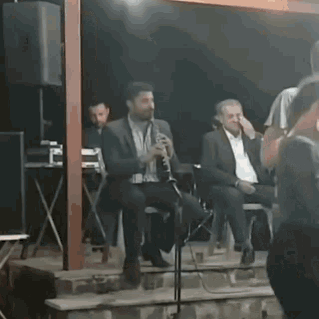 a man in a suit is playing a clarinet in front of a microphone
