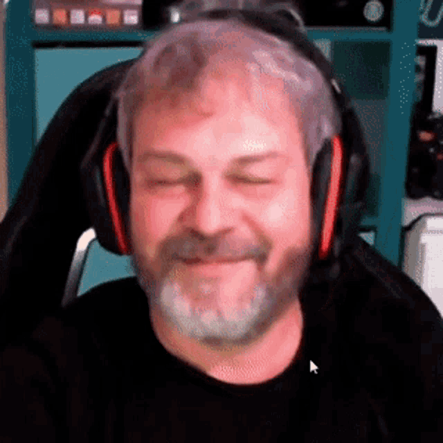 a man wearing headphones and a black shirt is smiling with his eyes closed