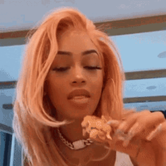 a woman with pink hair is eating a chicken nugget .