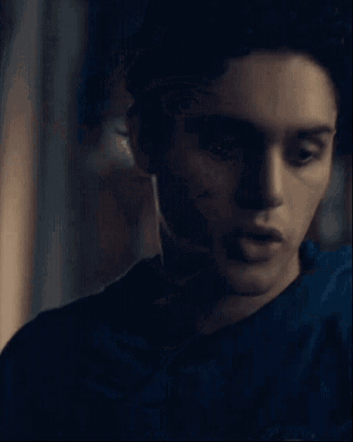 a close up of a young man 's face with a blue shirt on .