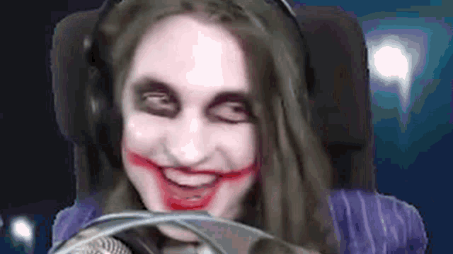 a woman is wearing headphones and making a joker face with red paint on her face .