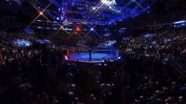 a crowd of people watching a boxing match in a stadium with a sign that says speck on it