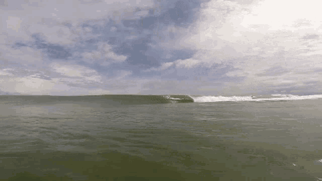 a surfer rides a wave in the ocean on a sunny day