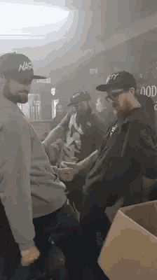 a group of men are standing in a room with smoke coming out of it .