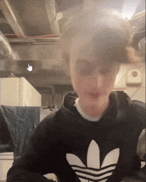 a young man wearing an adidas sweatshirt is looking at the camera