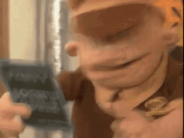 a close up of a cartoon character holding a cell phone in his hand .