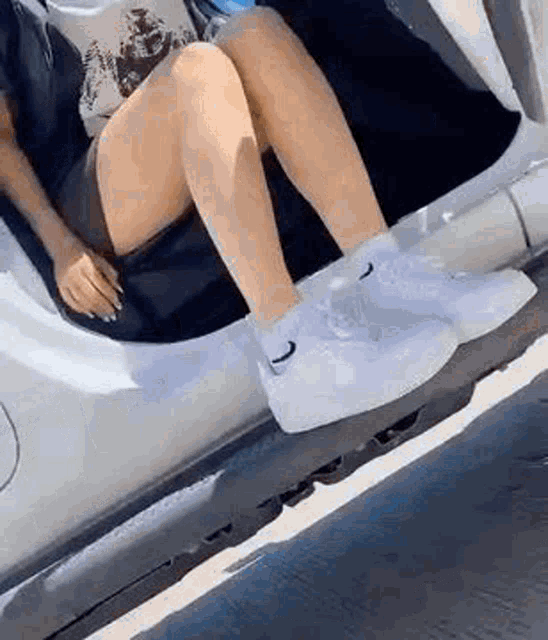a woman is sitting in the back seat of a car wearing nike air force 1 sneakers .