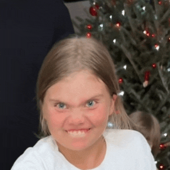 a little girl with a christmas tree in the background